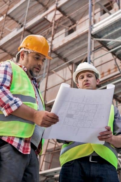 Construction surveyor and builder discussing site plans during a construction staking survey to ensure accurate layout