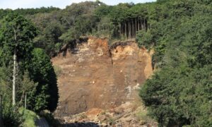 A steep hillside with exposed soil and erosion from a recent slope failure, showing the kind of hidden ground risks that drone surveying can reveal