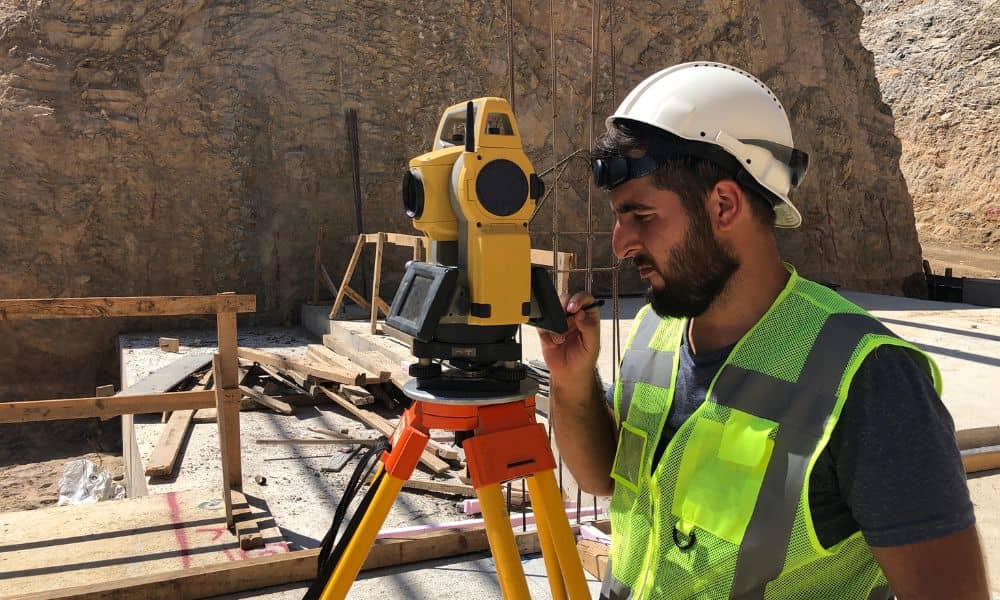 Engineer performing a construction survey using a total station on an active job site