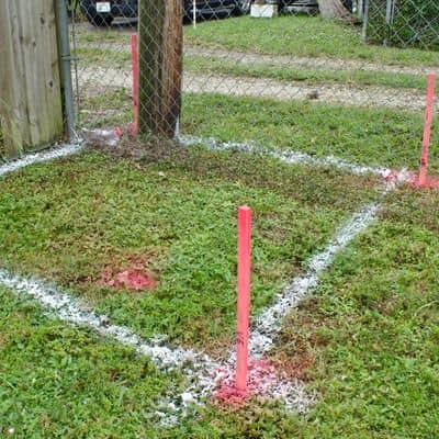 Survey stakes and painted markings showing a property line survey defining the legal boundary between yards