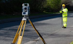 Surveyor performing a construction survey using a robotic total station on an active road project