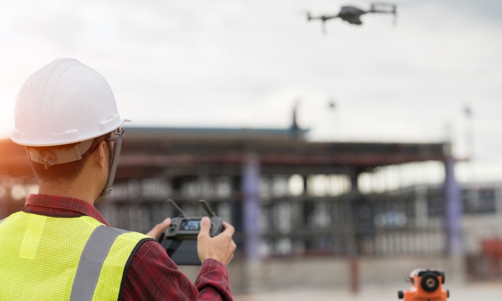 A licensed surveyor operating a drone during drone land surveying at an active construction site