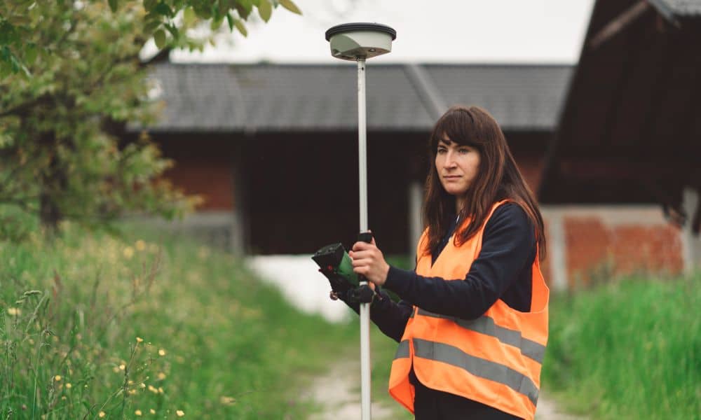 Surveyor using GNSS rover during a boundary line survey showing how GPS outages can cause delays
