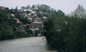 Flood elevation survey relevance shown by houses near a rising river with potential flood risk