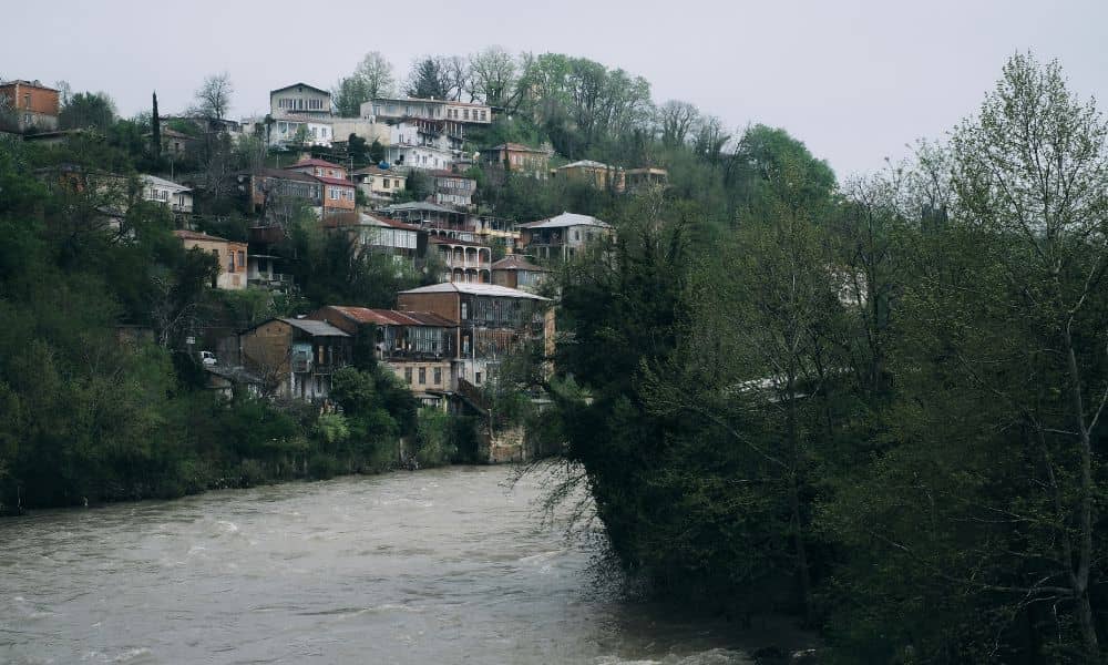 Flood elevation survey relevance shown by houses near a rising river with potential flood risk