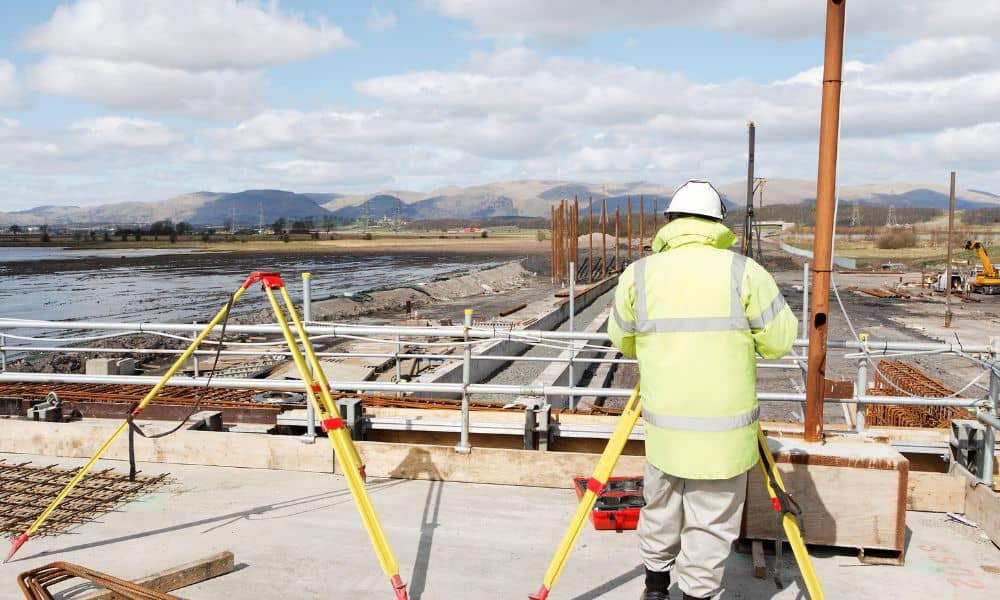 Construction surveyor using tripod equipment on an airport project site to ensure FAA Part 77 compliance
