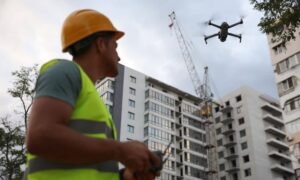 Drone land surveying at a construction site with a professional surveyor controlling the drone for mapping and site inspection