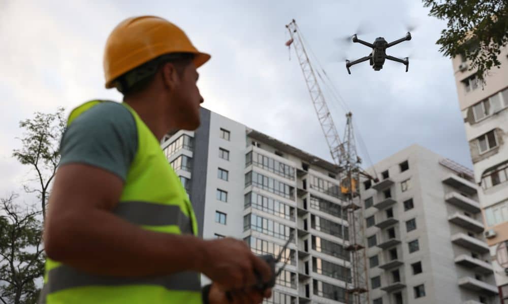 Drone land surveying at a construction site with a professional surveyor controlling the drone for mapping and site inspection