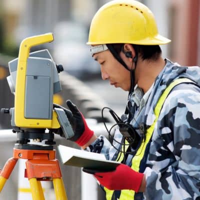 Licensed land surveyor measuring elevation data for a fema elevation certificate at a residential property