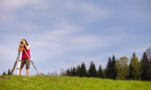 Licensed land surveyor using surveying equipment in the field