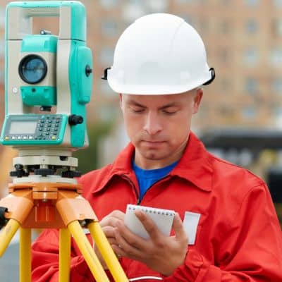 Licensed surveyor recording measurements while conducting an elevation survey on a residential property