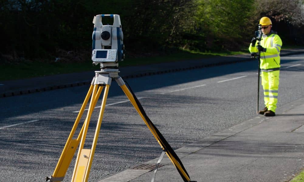 Surveyor performing a construction survey using a robotic total station on an active road project