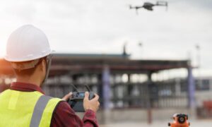 A licensed surveyor operating a drone during drone land surveying at an active construction site