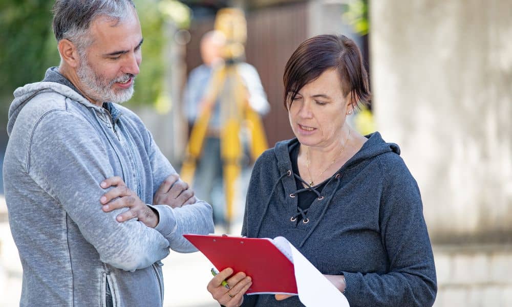 Homeowners discussing property lines with a surveyor during a boundary survey to clarify property limits